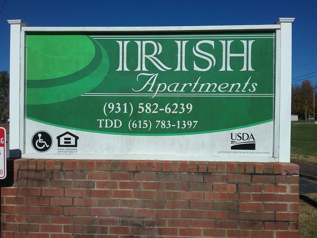 a sign apartments in front of a brick wall